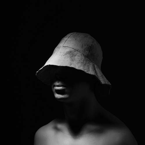 person grayscale photo of topless man wearing bucket hat black-and-white
