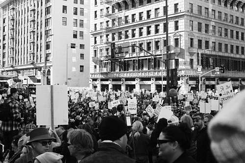 black-and-white grayscale photography of people protesting in front of concrete building crowd