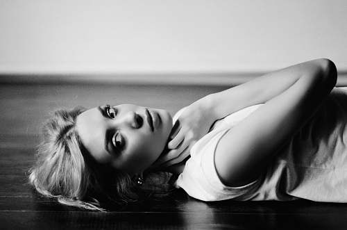 person grayscale photography of woman lying on parquet floor black-and-white