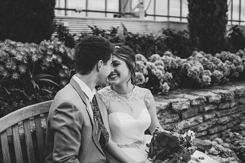 human grayscape photo of newlywed sitting on bench black-and-white