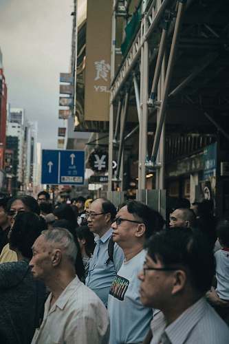 human group of men standing beside building under gray sky person