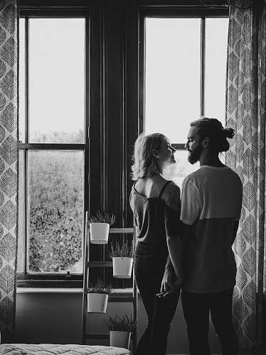 black-and-white man and woman facing each other near window plant