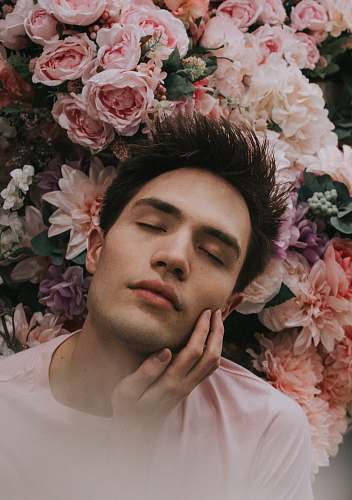 person man closing eye beside pink flower human