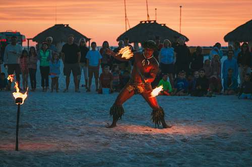 human man dancing fire dance surrounded by people at beach person