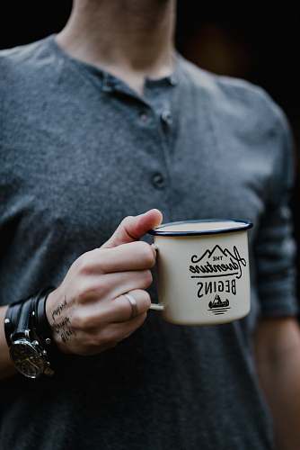 person man holding white ceramic mug cup