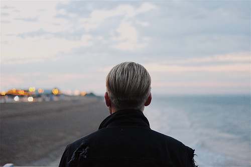 human man in black coat walking on seashore person