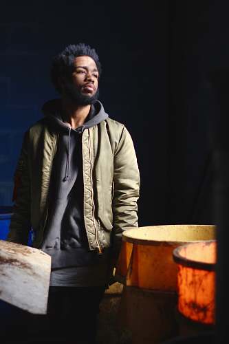person man in green and black jacket standing near containers human