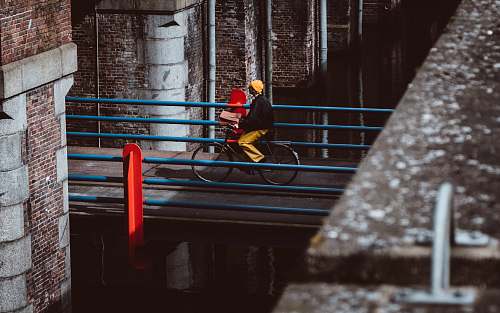 human man riding bicycle on gray concrete bridge during daytime person