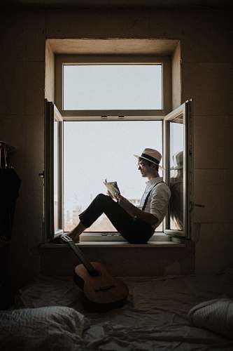 human man sitting on window while reading person