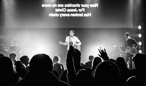 person man standing on stage and playing guitar black-and-white