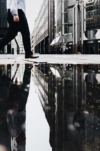 person man walking near puddle of water casting reflection human