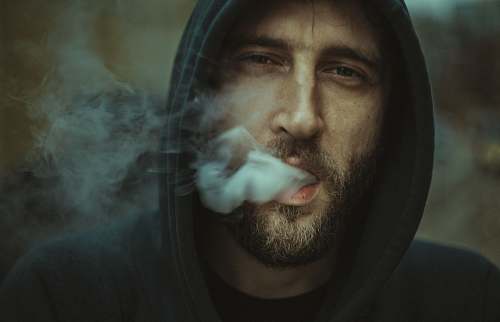 human man wearing black pullover hoodie blowing white smoke person