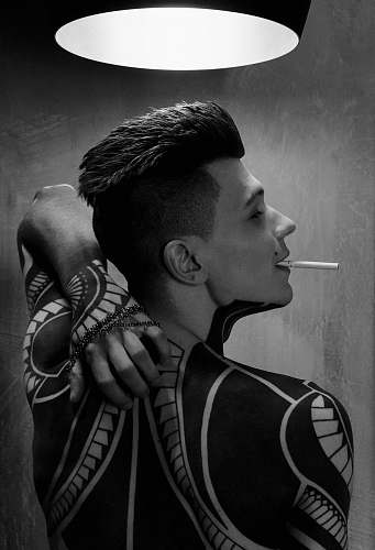human man with tattoo with white cigarette stick on mouth black-and-white