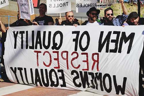 banner men holding white, black, and red Men of quality respect womens equality banner on road beard
