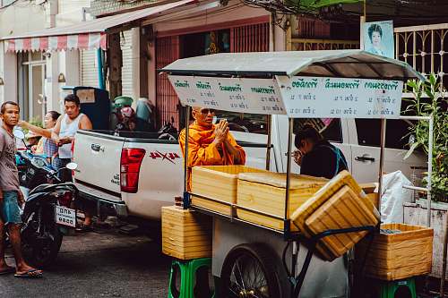 person monk on front of food kiosk near pickup truck human