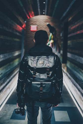 human person carrying black leather backpack holding camera person