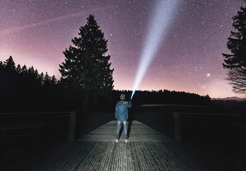 human person holding flashlight aiming on sky person