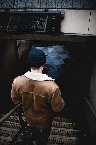 person person in brown jacket walking on the stair human