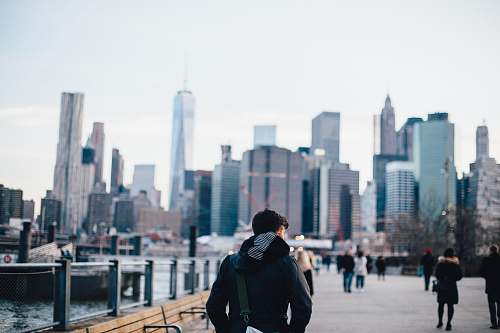 person selective focus photography of man standing near body of water walking towards buildings human