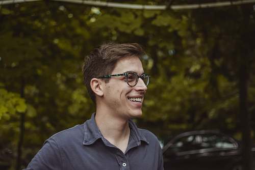 person smiling man wearing grey polo shirt and black framed eyeglasses human