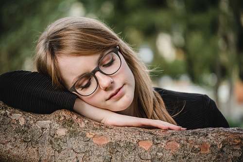 person tilt shift photography of woman sleeping on log human