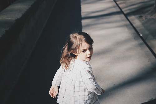 person toddler girl walking on gray concrete road at daytime human