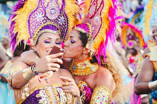 human Two women Carnival dancers pose for a selfie as one kisses other on the cheek. festival