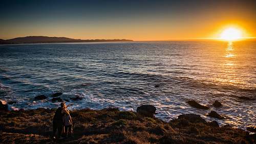 human woman and children standing in front of sea during sunset person