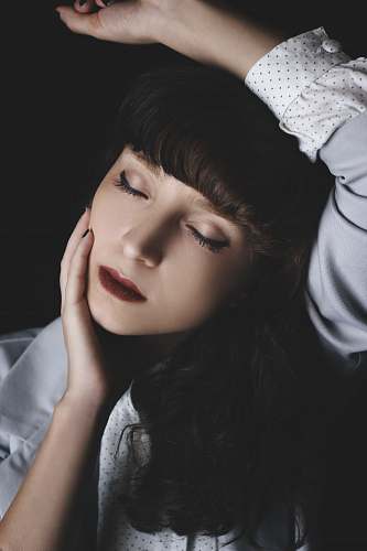 person woman holding her cheek while rising her right hand in black background human