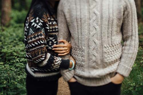 person woman in black and white sweater hugging man in gray cable knit sweater sweater