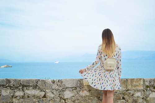 human woman in white dress looking at body of water person