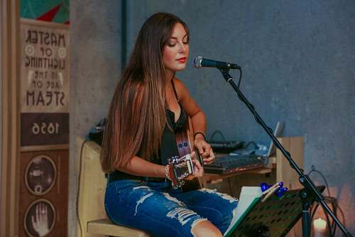 human woman playing guitar while singing person