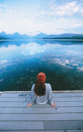 person woman sitting in front of calm body of water human