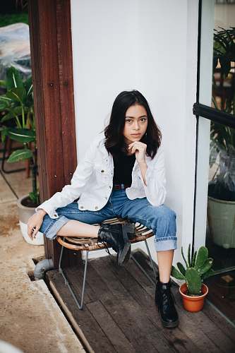 human woman sitting on brown chair near green plants plant