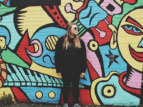 human woman standing beside wall with graffiti person
