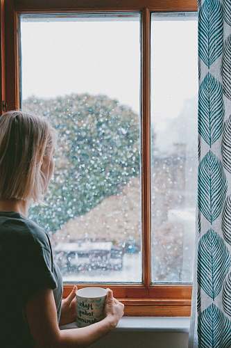 human woman standing in front of clear glass window cup