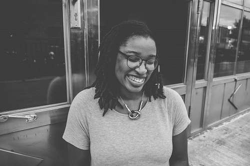 black-and-white woman standing near glass door grey