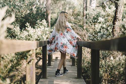 person woman walking along wooden foot bridge leading to forest human