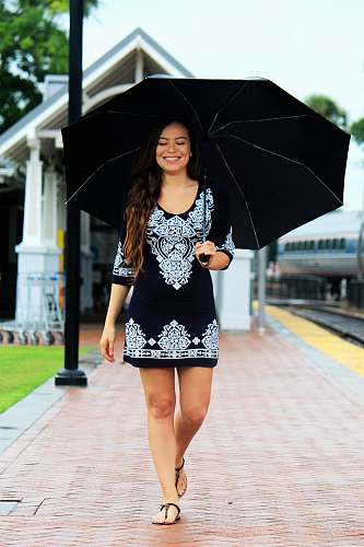 person woman walking on brown pathway while holding black umbrella human