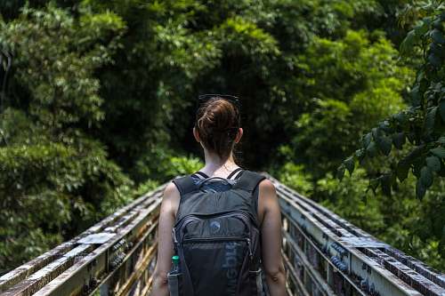person woman wearing backpack walking on bridge human