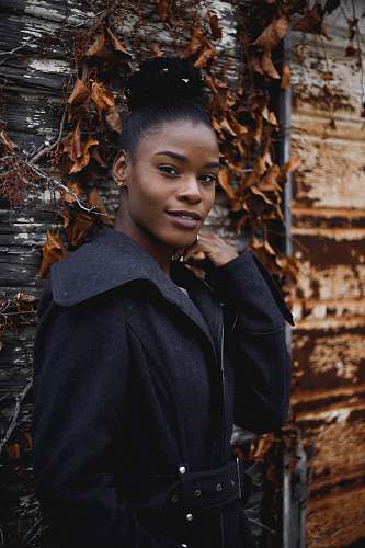person woman wearing black coat standing near dried leaves human