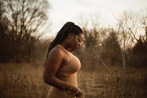 woman woman wearing brown tank top standing near grass human