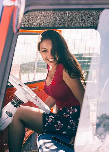 person woman wearing red tank top and multicolored floral skirt while sitting inside vehicle human