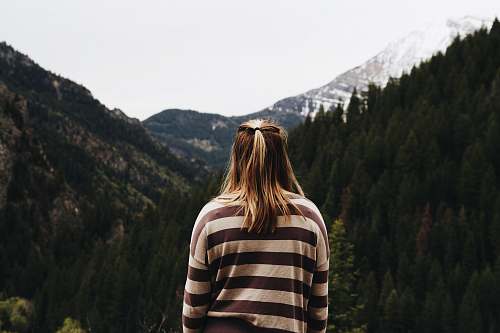 person woman wearing striped long-sleeved shirt facing mountains human
