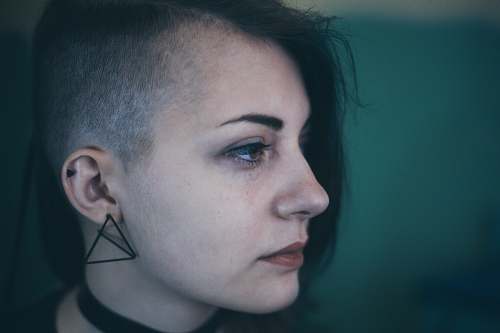 person Woman with an edgy shaved haircut looks sad and defeated human