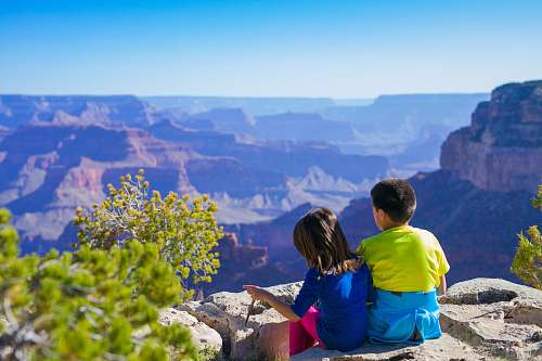 human boy sitting beside girl in blue shirt near green leafed tree people