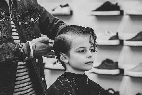 people greyscale photo of boy having a haircut black-and-white