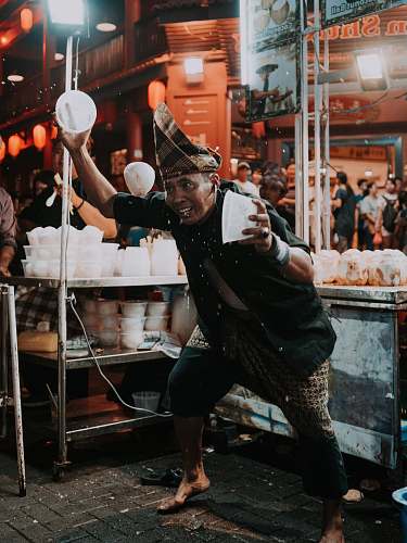 people man holding two white plastic bowls near food stall human