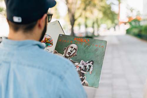 people man holding vinyl album in shallow focus photography human