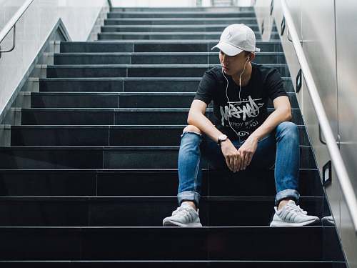 human man sitting on black staircase while listening people